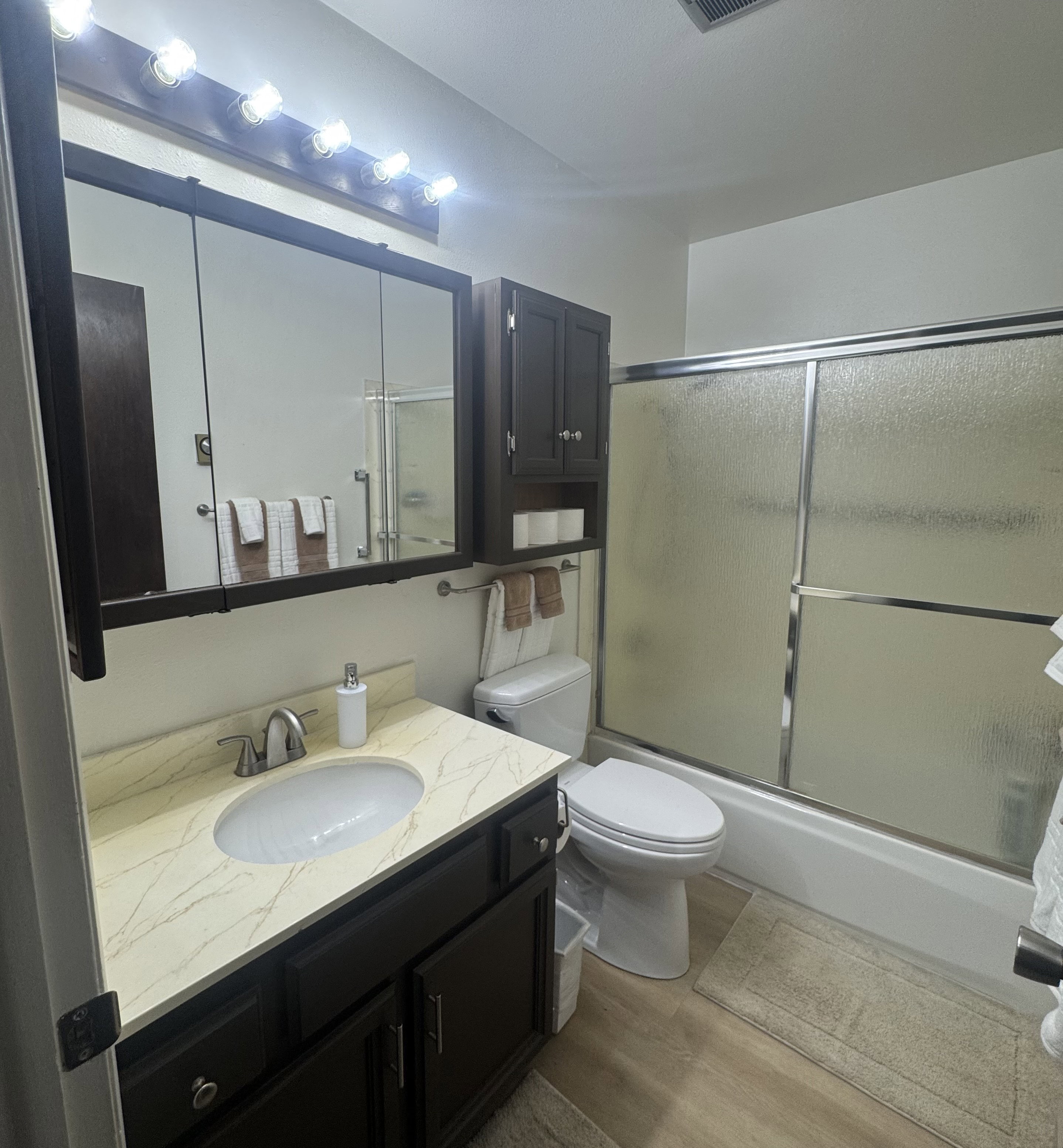 Full bath featuring vanity, enclosed tub / shower combo, and LVP finished floors