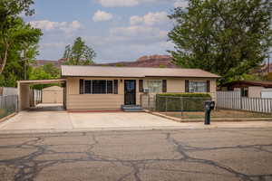 Single story home with driveway, metal roof, an attached carport, a mountain view, and a gate