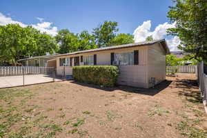 Back of property featuring a gate, a fenced backyard, metal roof, a carport, and concrete driveway