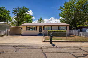 Ranch-style house featuring a fenced front yard, metal roof, driveway, and a carport