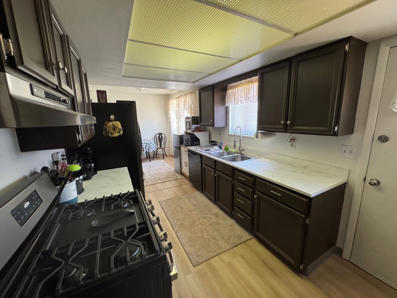 Kitchen featuring black appliances, light wood-style floors, new  countertops, and under cabinet range hood
