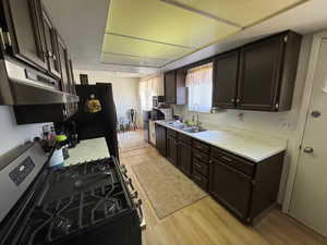 Kitchen featuring black appliances, light wood-style floors, new  countertops, and under cabinet range hood