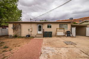 Rear view of property featuring entry steps, an attached carport, fence, and metal roof