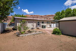 Rear view of house featuring fence, metal roof, a patio, a mountain view, and a vegetable garden