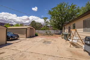 View of patio / terrace with a storage unit, a fenced backyard, and an outdoor structure