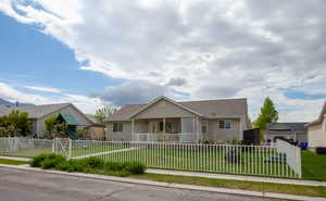View of front of house with a fenced front yard, covered porch, a front yard, roof with shingles, and a playground