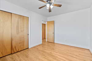 Unfurnished bedroom with baseboards, light wood-style floors, a closet, and a ceiling fan