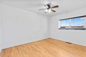 Spare room featuring baseboards, visible vents, and wood finished floors