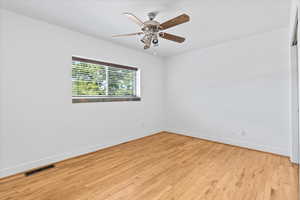 Spare room with light wood-type flooring, visible vents, baseboards, and ceiling fan