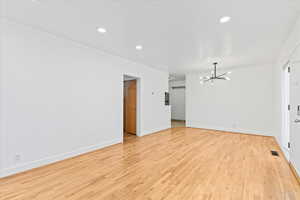 Unfurnished living room featuring light wood finished floors, a notable chandelier, baseboards, and recessed lighting