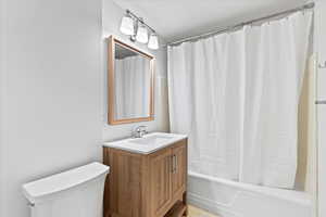Bathroom with toilet, shower / tub combo, and vanity