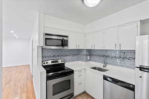 Kitchen with a sink, decorative backsplash, light countertops, and appliances with stainless steel finishes