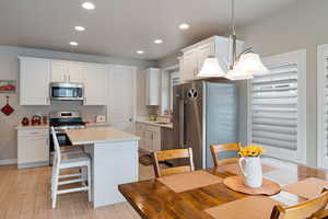 Kitchen featuring appliances with stainless steel finishes, light wood-style flooring, a center island, white cabinets, and recessed lighting