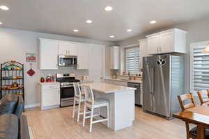 Kitchen with appliances with stainless steel finishes, a sink, light countertops, white cabinetry, and recessed lighting