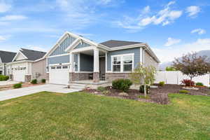 Craftsman-style home with board and batten siding, driveway, stone siding, covered porch, and a garage