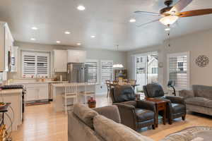 Living room with a ceiling fan, light wood finished floors, and recessed lighting