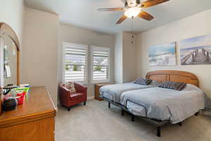 Bedroom with light carpet, a ceiling fan, and baseboards