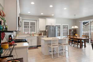 Kitchen with appliances with stainless steel finishes, a sink, light countertops, light wood finished floors, and white cabinetry