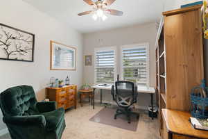 Office area featuring light carpet, ceiling fan, and baseboards