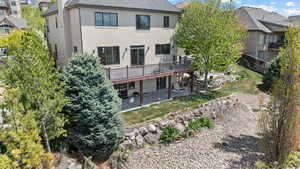 Rear view of property with fence, a patio area, stucco siding, a wooden deck, and a lawn