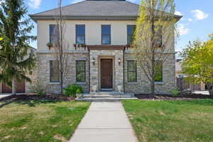 View of front of property featuring fence, stucco siding, a front lawn, and stone siding