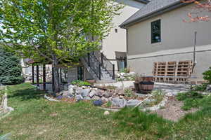 View of side of home with a lawn, a patio, an attached garage, stucco siding, and stairway