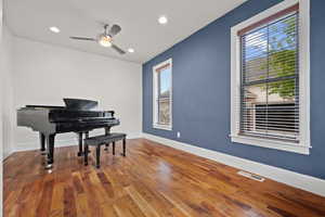 Sitting room with a ceiling fan, visible vents, wood finished floors, and baseboards