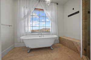 Full bath featuring a freestanding bath, plenty of natural light, and a chandelier