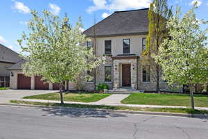 View of front of home featuring driveway, an attached garage, stucco siding, stone siding, and roof with shingles