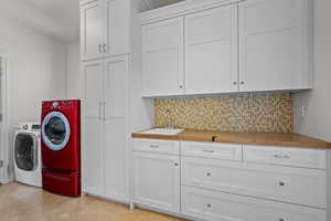 Washroom featuring cabinet space, washing machine and dryer, wet bar, and a sink