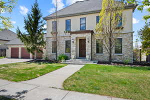 View of front facade featuring stone siding, stucco siding, and a front lawn