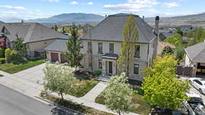 Traditional home with stone siding, an attached garage, a residential view, stucco siding, and fence