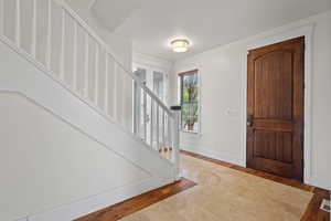 Foyer featuring baseboards, stairs, and wood finished floors