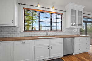 Kitchen with wood counters, tasteful backsplash, a sink, and dishwasher
