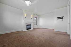 Unfurnished living room featuring carpet flooring, baseboards, and a high end fireplace