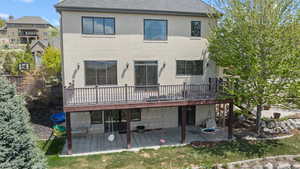 Rear view of property featuring roof with shingles, a wooden deck, a patio, and stucco siding