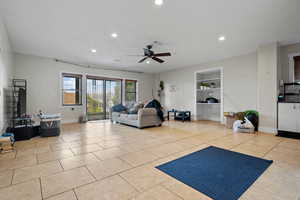 Living room with a ceiling fan, baseboards, recessed lighting, and built in shelves
