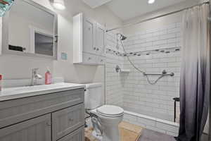 Bathroom featuring vanity, toilet, tiled shower, and recessed lighting