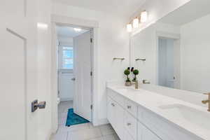 Full bath featuring toilet, tile patterned flooring, double vanity, and a sink