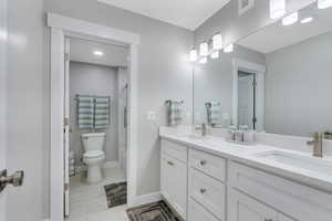 Full bathroom featuring double vanity, toilet, visible vents, and a sink
