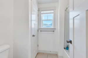 Bathroom featuring tile patterned floors, toilet, a shower, and baseboards