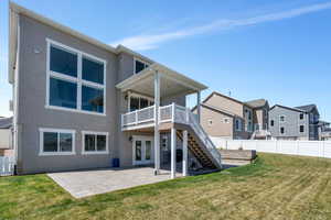 Rear view of property with a yard, stucco siding, french doors, and stairway