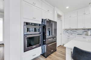 Kitchen with stainless steel appliances, recessed lighting, light countertops, white cabinets, and light wood-style floors