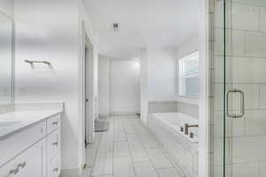 Bathroom with a garden tub, a stall shower, visible vents, baseboards, and vanity