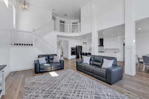 Living room with stairway, a high ceiling, and light wood-style floors
