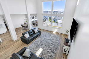Living room featuring a chandelier, a towering ceiling, baseboards, and light wood finished floors