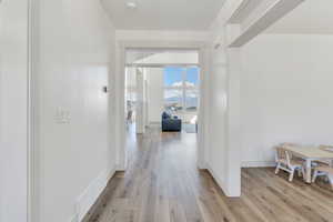 Hallway with baseboards, visible vents, and light wood-style floors