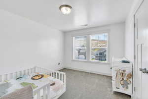 Bedroom with baseboards, a crib, visible vents, and carpet floors