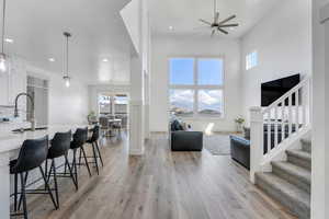 Living room featuring light wood-style flooring, stairway, a towering ceiling, ceiling fan, and recessed lighting