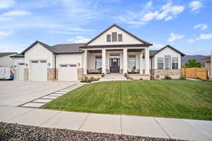 View of front of home featuring board and batten siding, a porch, stone siding, a garage, and driveway